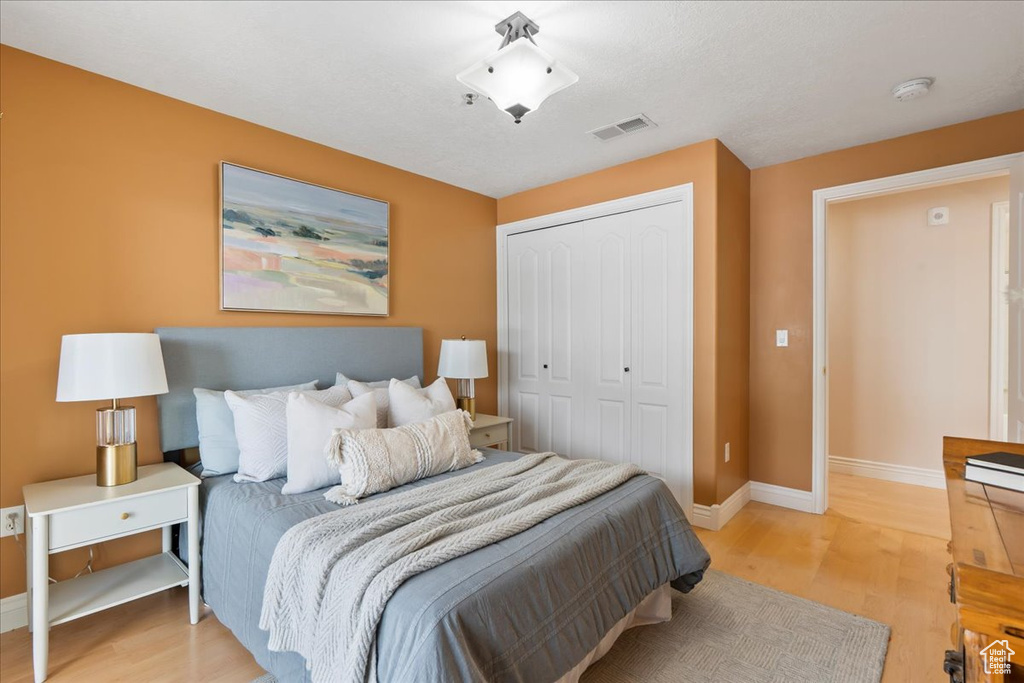 Bedroom featuring light wood-style flooring, a closet, and baseboards