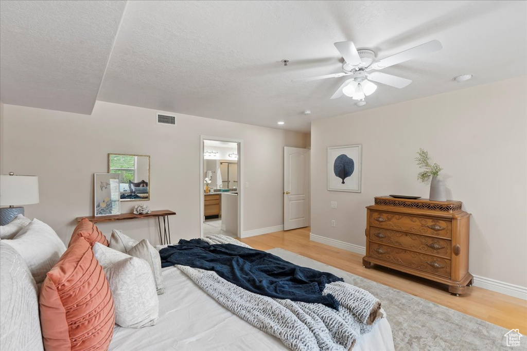 Bedroom with light wood finished floors, baseboards, connected bathroom, and recessed lighting