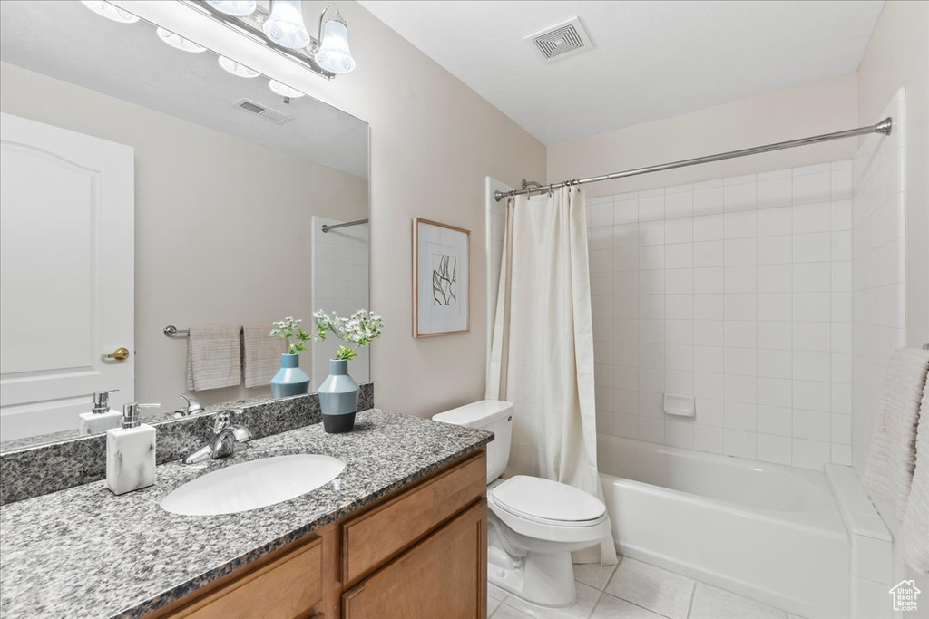 Full bath with tile patterned floors, toilet, shower / bathtub combination with curtain, and vanity
