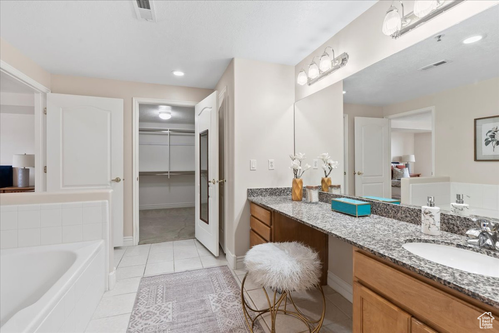 Full bath with tile patterned floors, vanity, a bath, and baseboards
