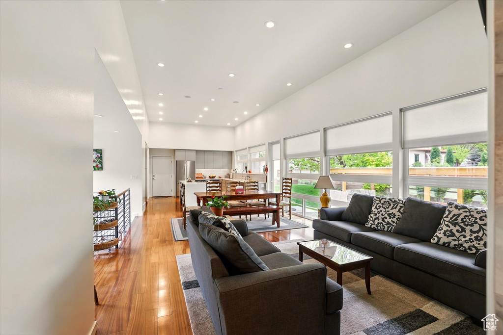 Living area with recessed lighting, a towering ceiling, and light wood-style floors