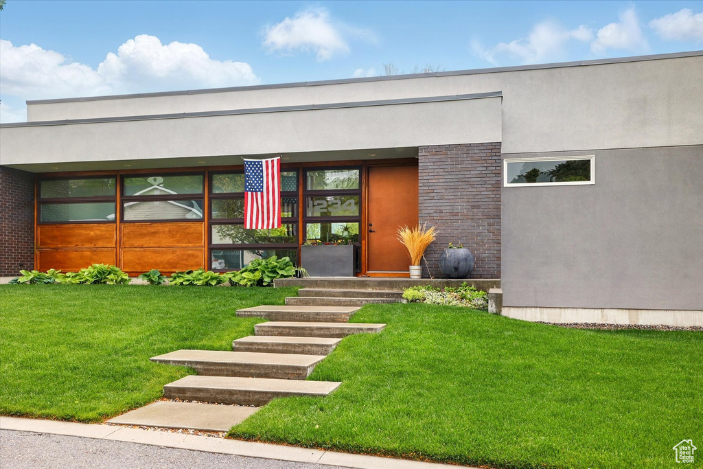 Entrance to property with a lawn and stucco siding