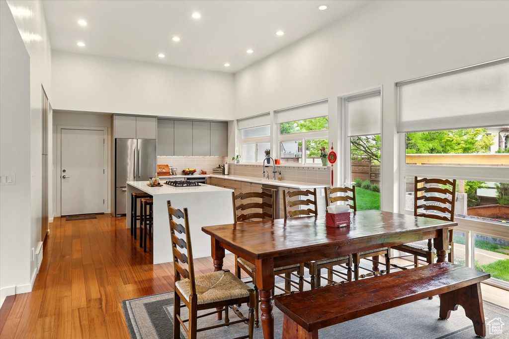 Dining room with a high ceiling, plenty of natural light, recessed lighting, and light wood-type flooring