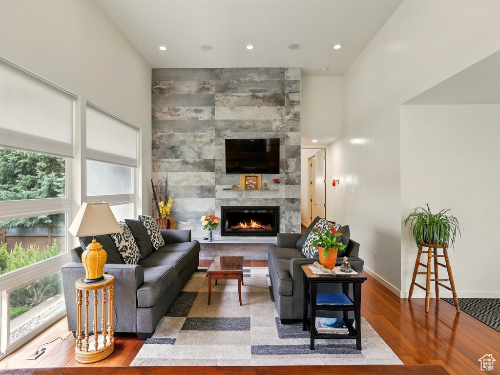 Living room featuring plenty of natural light, wood finished floors, a tile fireplace, baseboards, and recessed lighting