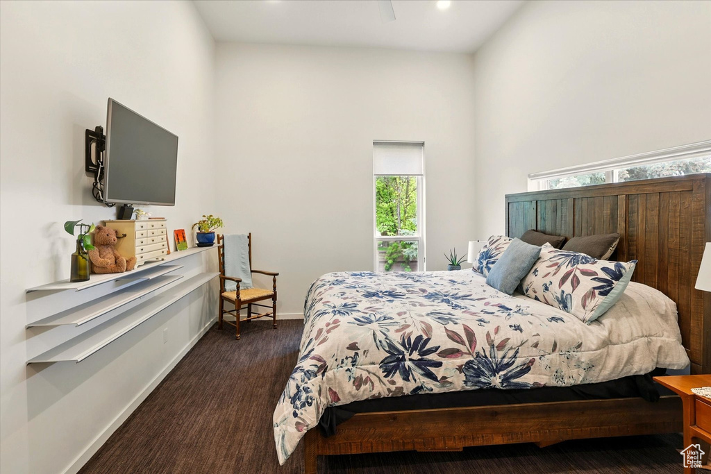 Bedroom with baseboards, a towering ceiling, and dark colored carpet