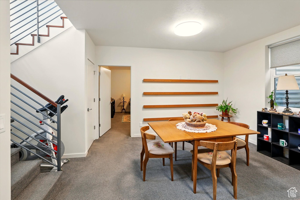 Carpeted dining space with stairs and baseboards
