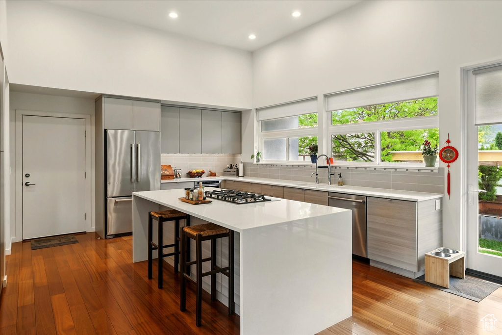 Kitchen featuring stainless steel appliances, gray cabinetry, modern cabinets, a breakfast bar area, and recessed lighting