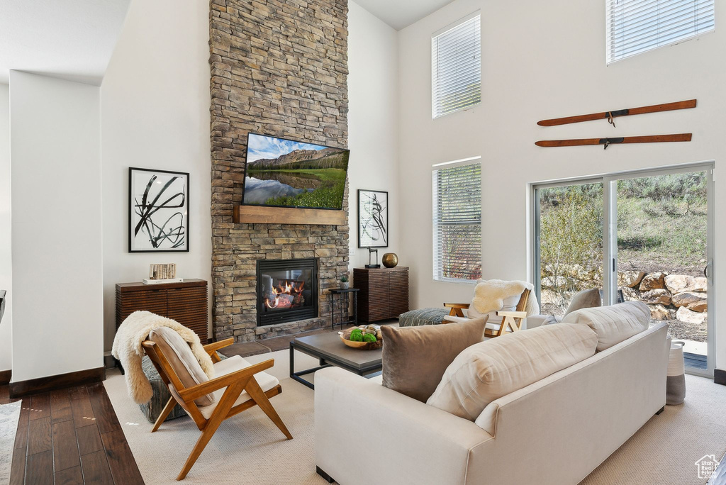 Living area with a fireplace, a towering ceiling, hardwood / wood-style floors, and baseboards