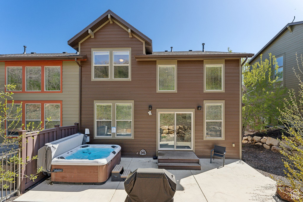 Rear view of house with a hot tub and a patio area
