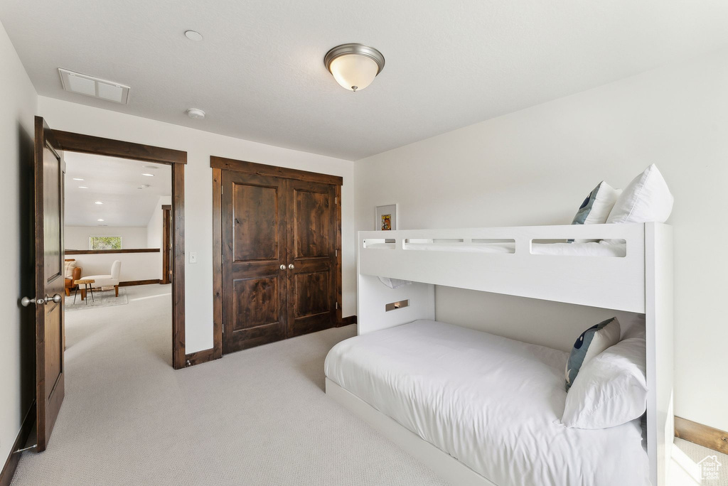 Bedroom with light carpet, a closet, and baseboards