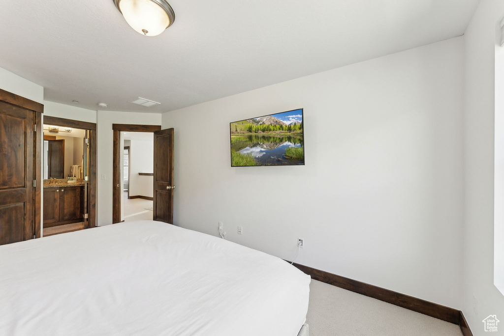 Bedroom with carpet, ensuite bathroom, and baseboards