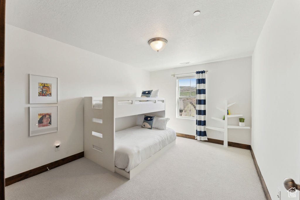 Bedroom with carpet floors, baseboards, and a textured ceiling