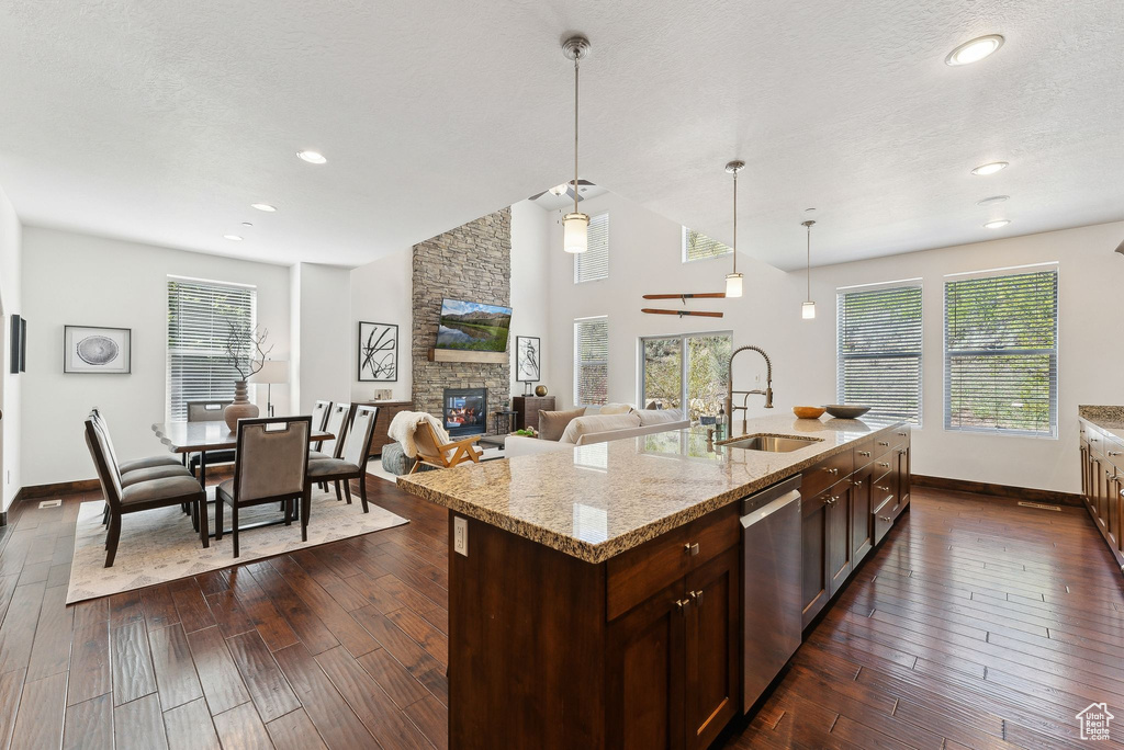Kitchen with a sink, stainless steel dishwasher, baseboards, healthy amount of natural light, and vaulted ceiling