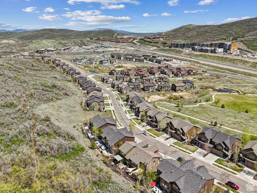 Aerial view of property and surrounding area featuring nearby suburban area and a mountain backdrop