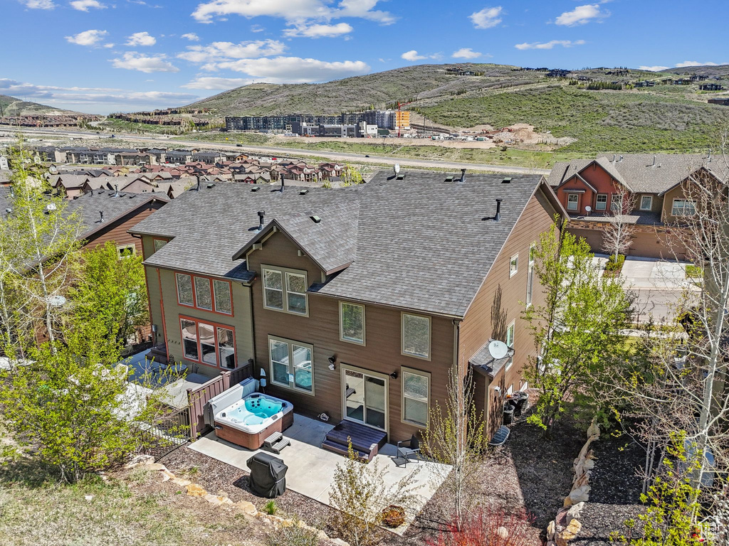 Back of property with a mountain view, a patio area, a shingled roof, and fence