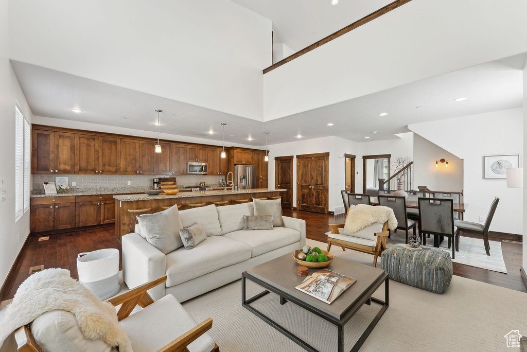 Living area with dark wood-style flooring, recessed lighting, baseboards, and stairs