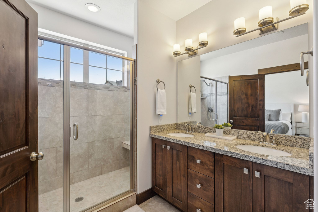 Bathroom featuring ensuite bathroom, a stall shower, and double vanity