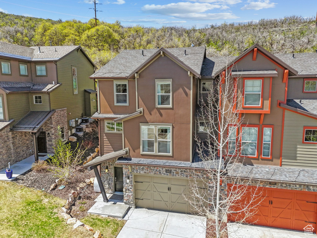 Townhome / multi-family property with a garage, concrete driveway, stucco siding, and stone siding