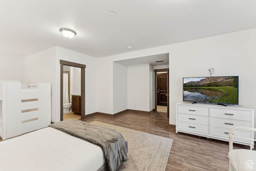 Bedroom featuring wood finished floors, baseboards, and ensuite bathroom