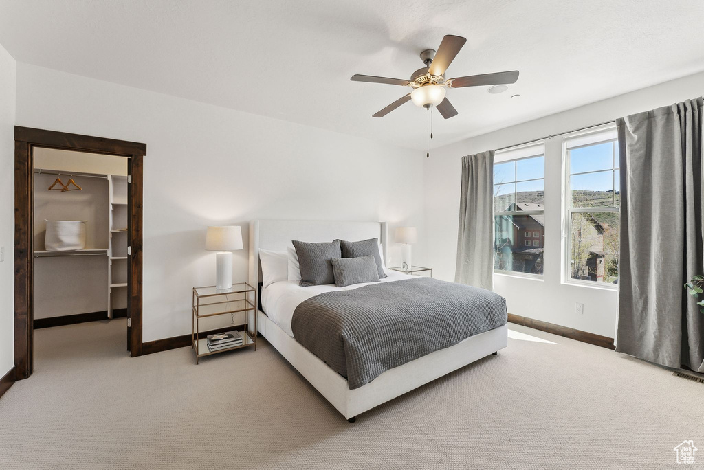 Bedroom featuring carpet, baseboards, a walk in closet, and a ceiling fan