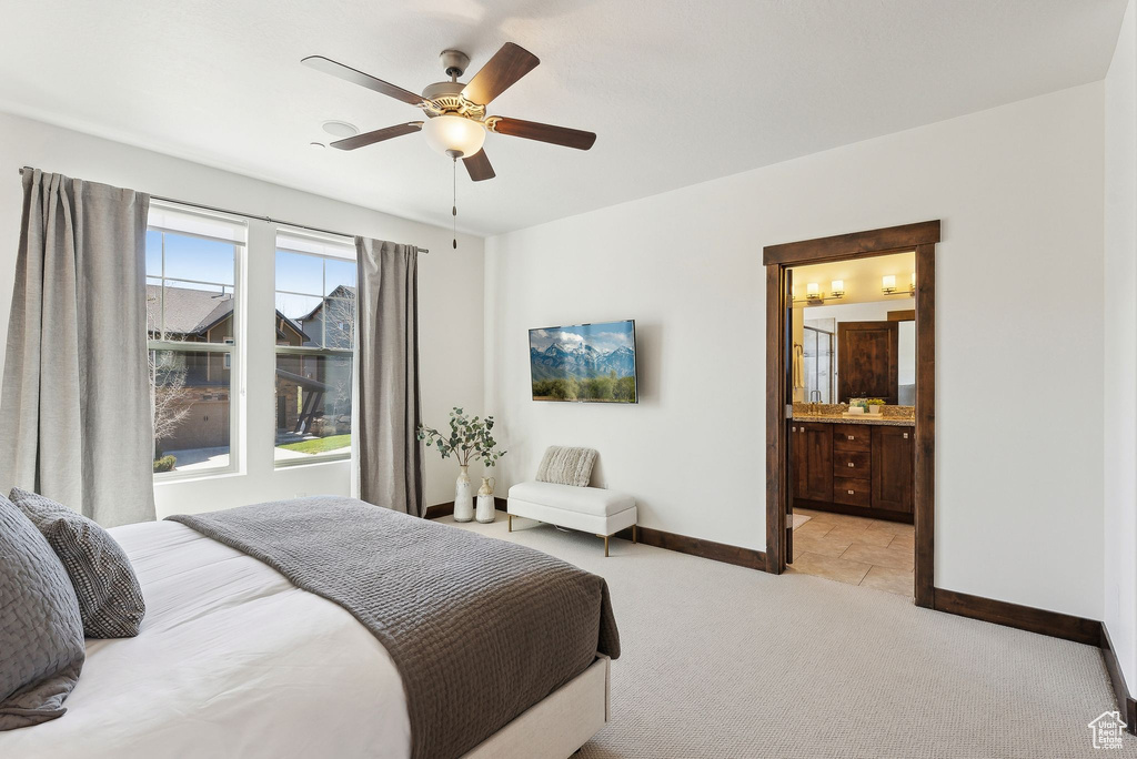 Bedroom with baseboards, light carpet, a ceiling fan, and ensuite bathroom