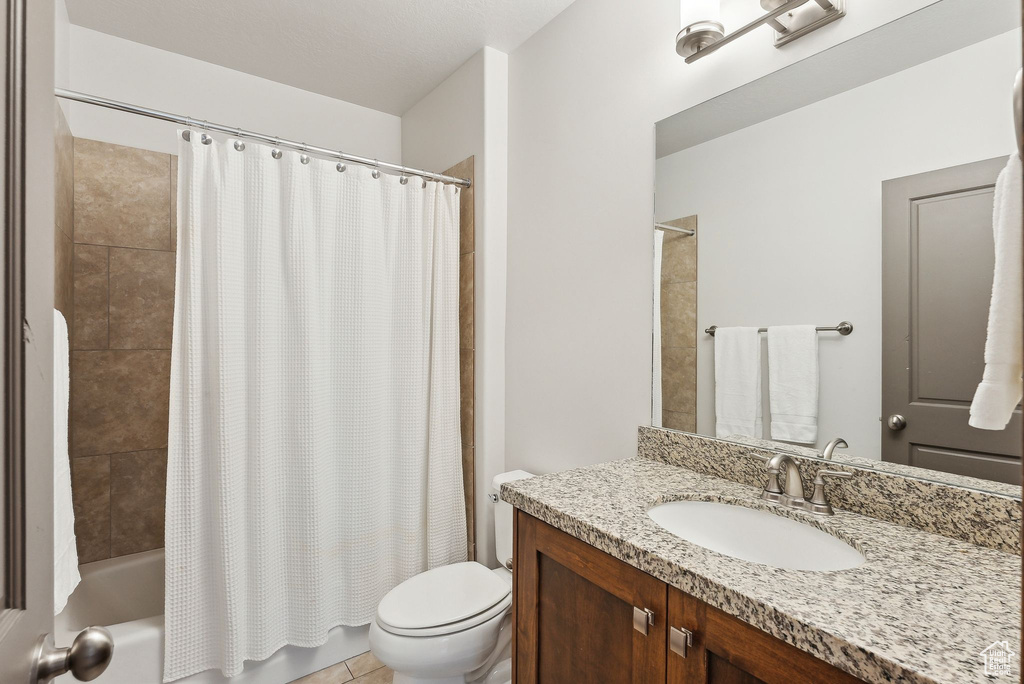 Full bathroom with toilet, shower / tub combo with curtain, and vanity