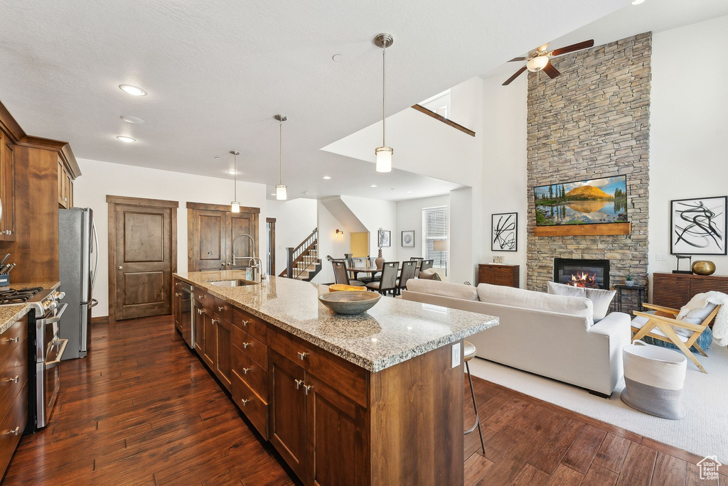 Kitchen with a sink, appliances with stainless steel finishes, a breakfast bar area, dark wood-type flooring, and a ceiling fan