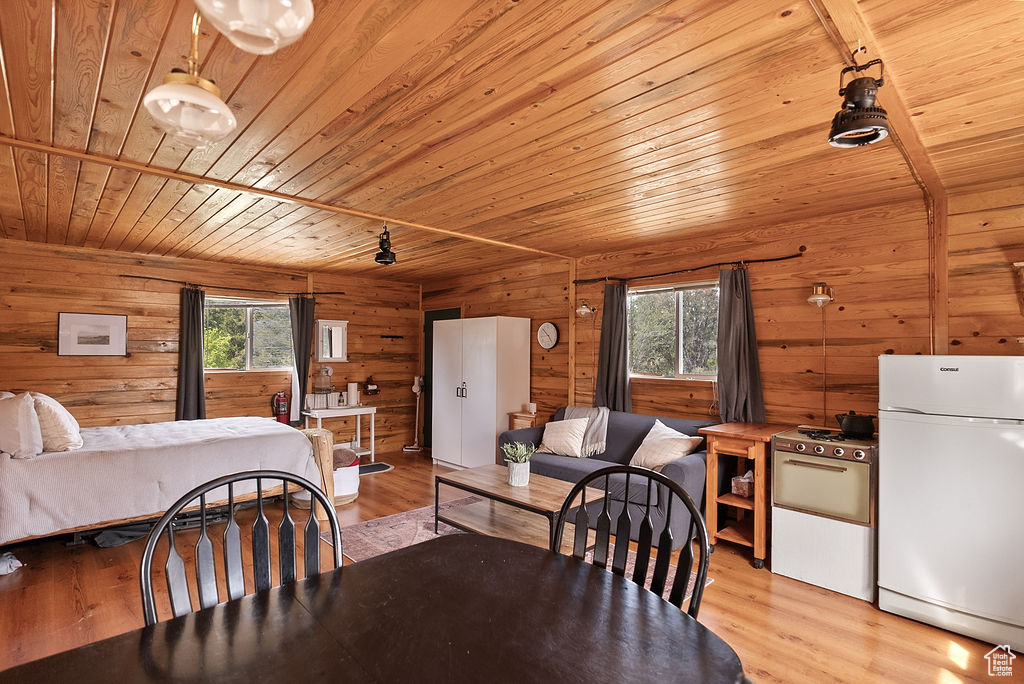 Dining room featuring wood ceiling, healthy amount of natural light, wooden walls, and light wood finished floors