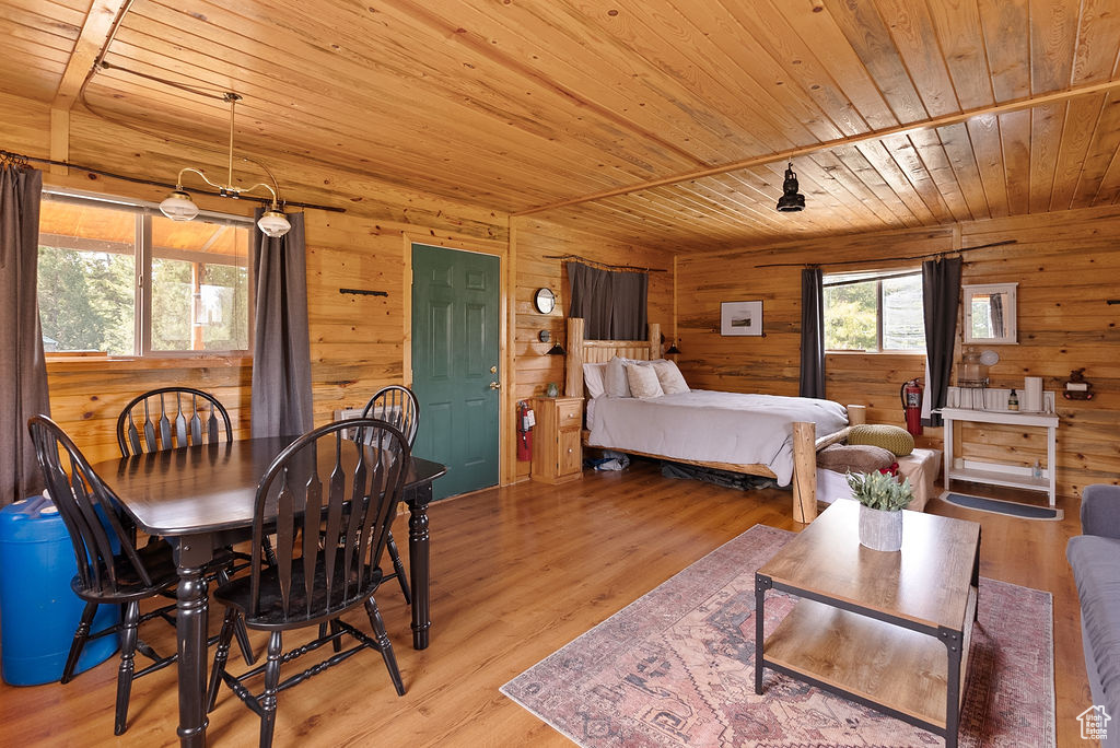 Bedroom with wood ceiling, wood walls, and light wood-style floors