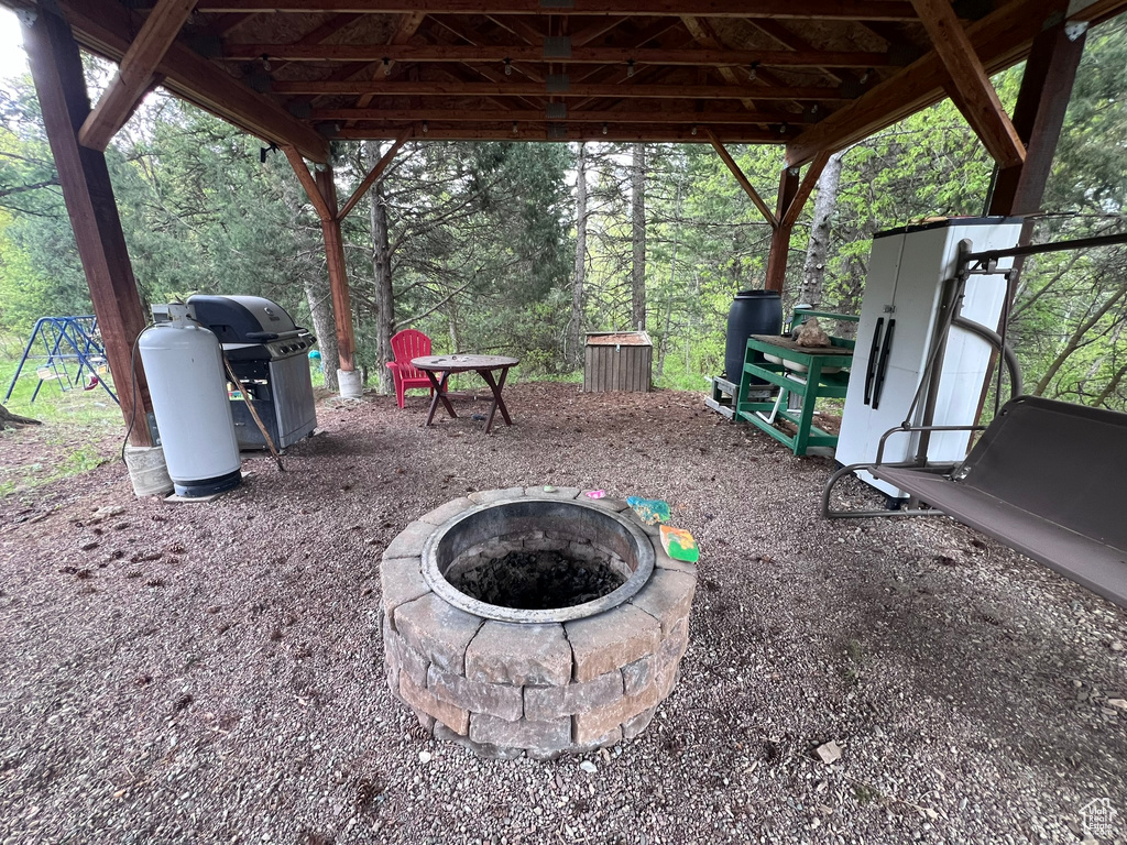 View of patio with a fire pit and area for grilling