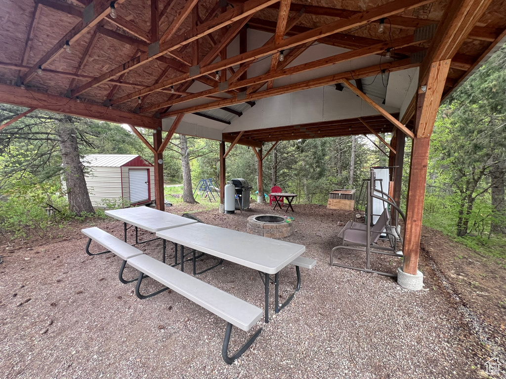 View of patio with an outdoor structure, a fire pit, a storage shed, and grilling area