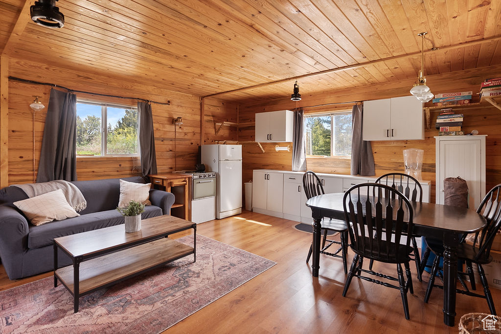 Dining room featuring wood ceiling, wooden walls, and light wood-style floors