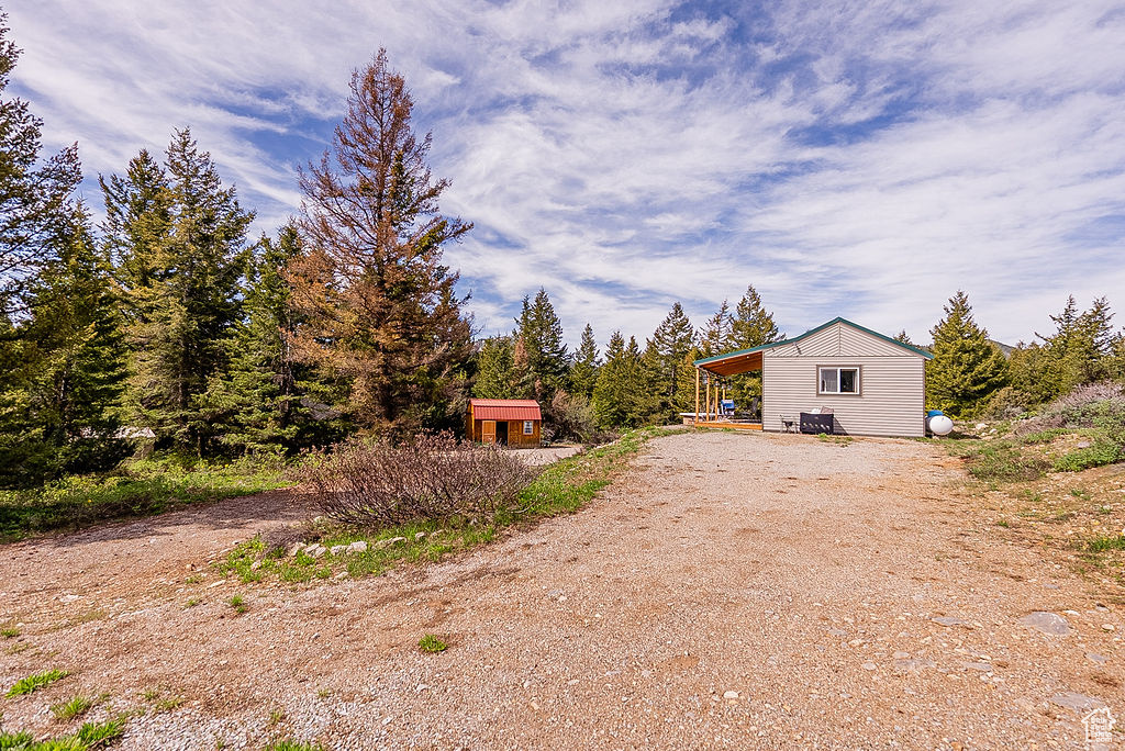 View of side of property with dirt driveway, an outbuilding, and a storage unit