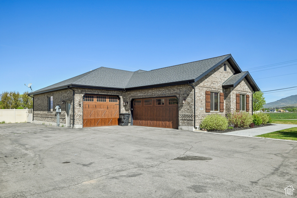 View of home's exterior with brick siding, a garage, a shingled roof, and driveway