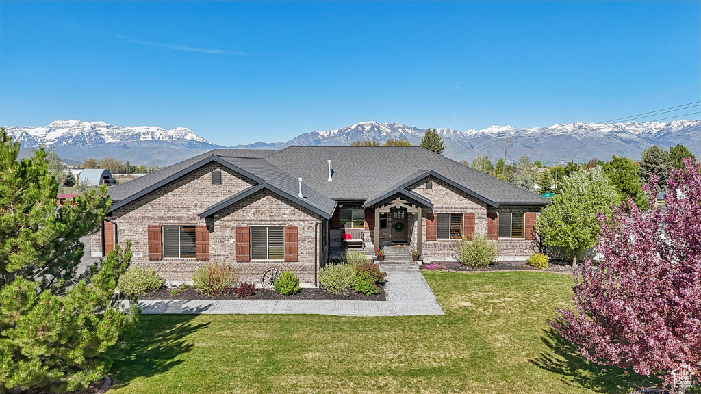View of front of home with brick siding, a mountain view, and a front yard