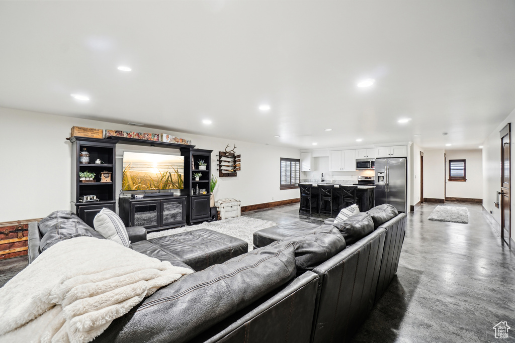 Living area featuring baseboards, concrete flooring, and recessed lighting