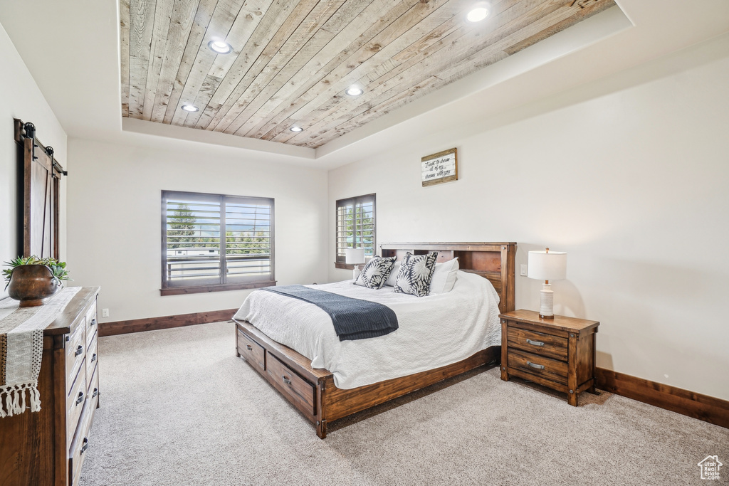 Carpeted bedroom featuring a tray ceiling, wood ceiling, recessed lighting, baseboards, and a barn door