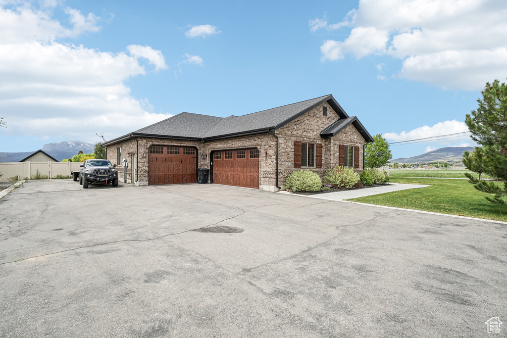 View of front of home featuring brick siding, a garage, a mountain view, driveway, and a shingled roof