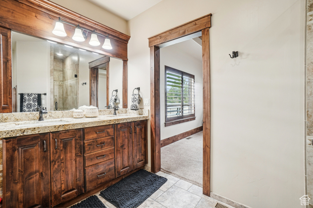 Bathroom featuring a shower stall, tile patterned flooring, double vanity, and baseboards