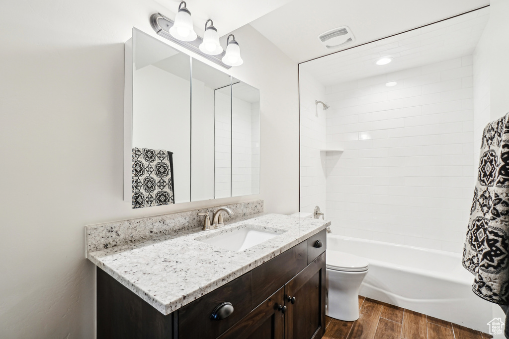 Bathroom featuring wood finished floors, toilet, vanity, and shower / bath combination