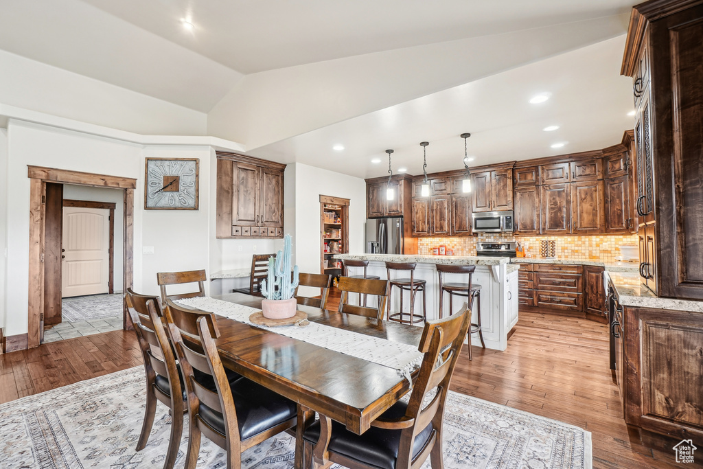 Dining area with light wood-type flooring, lofted ceiling, and recessed lighting