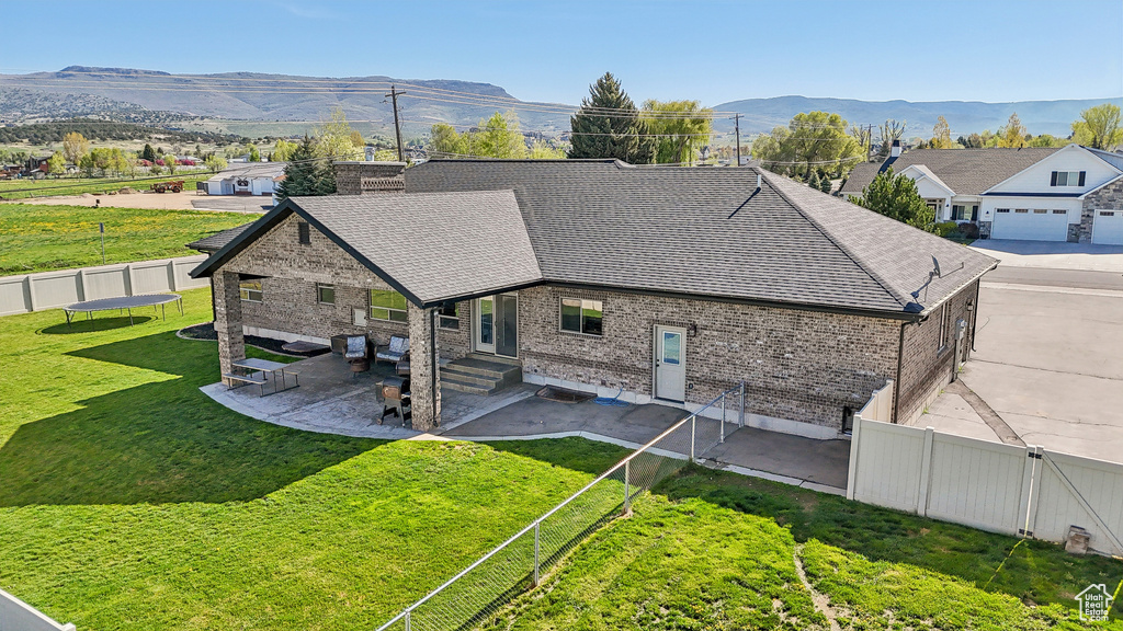 Rear view of house with roof with shingles, brick siding, a patio, entry steps, and a mountain view