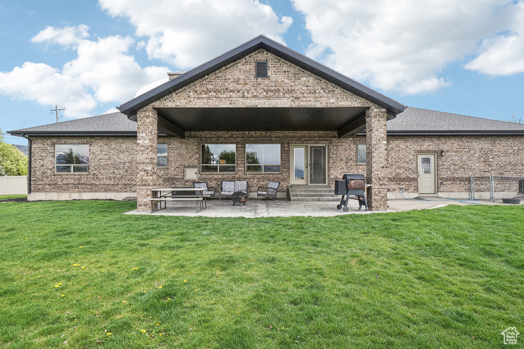 Rear view of property featuring entry steps, brick siding, a patio, and a shingled roof