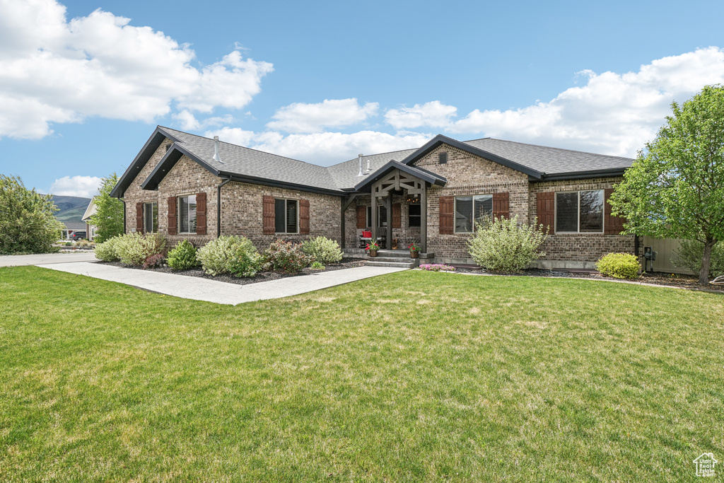 View of front of house featuring brick siding, a front lawn, and roof with shingles