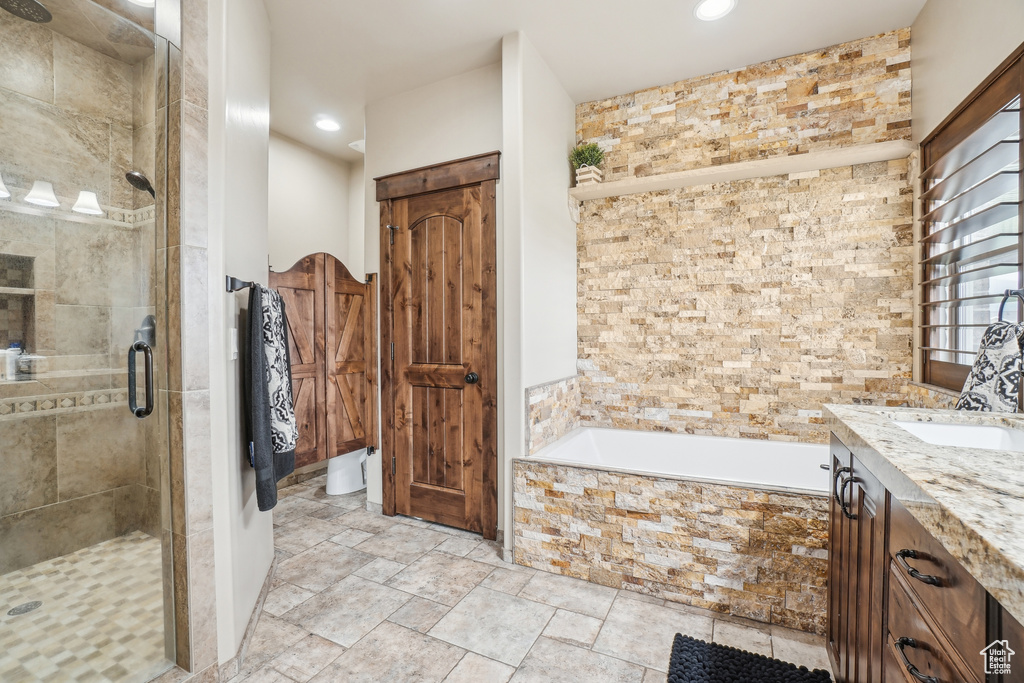 Full bath featuring a shower stall, a garden tub, vanity, recessed lighting, and stone finish floors