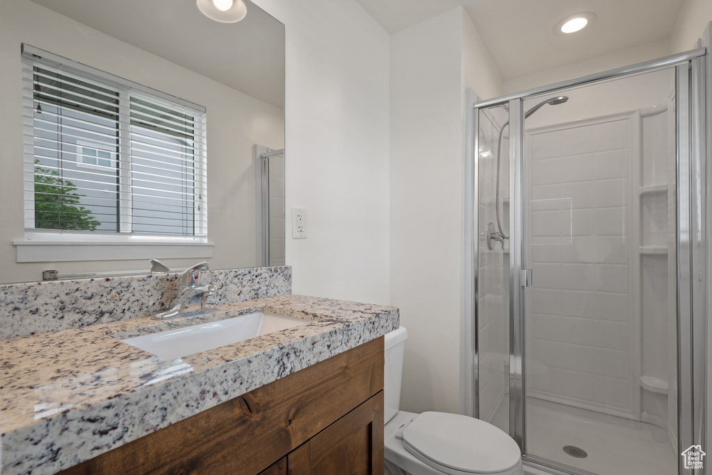 Full bathroom with toilet, a stall shower, vanity, and recessed lighting