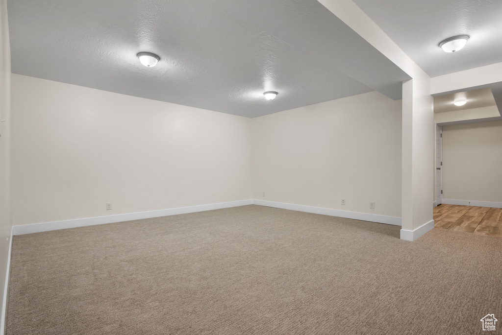 Finished basement featuring carpet, baseboards, and a textured ceiling