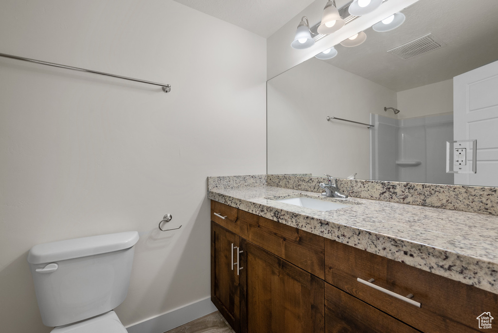 Bathroom with toilet, baseboards, vanity, and a shower