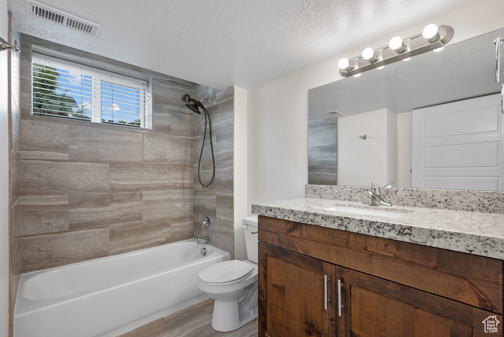 Full bath with toilet, shower / washtub combination, vanity, wood finished floors, and a textured ceiling