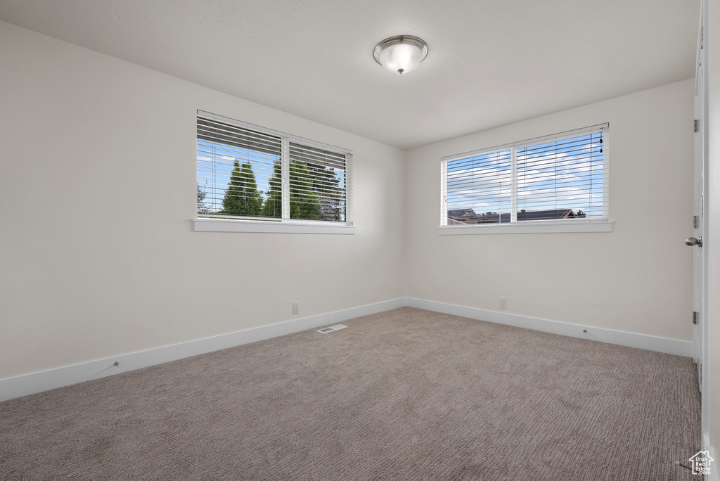 Empty room featuring baseboards and carpet flooring